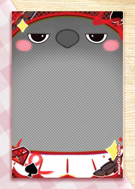 A rectangular notepad with a crow's face design, shown on a light wood background with a pink patterned border. The face has black eyes, pink cheeks, and a gray dotted area with small black and red decorative symbols.