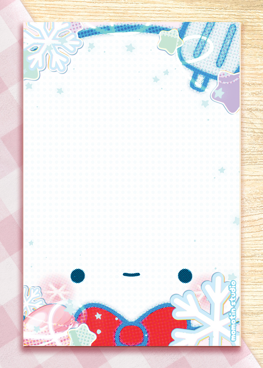 A rectangle white notepad with a cute winter-themed border design, featuring a smiling face, snowflakes, shown on a pink and wood background.