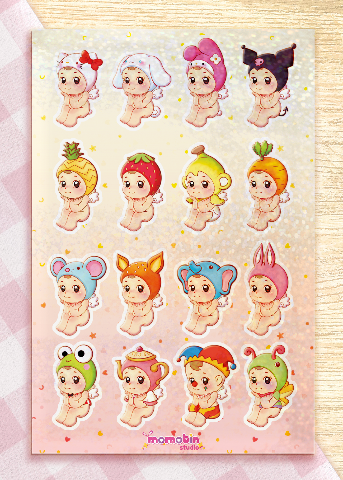 A sheet of cute cartoon baby stickers arranged in a grid on a pink glittery laminate. Each sticker shows a different adorable character in various playful outfits and animal or fruit-inspired costumes.