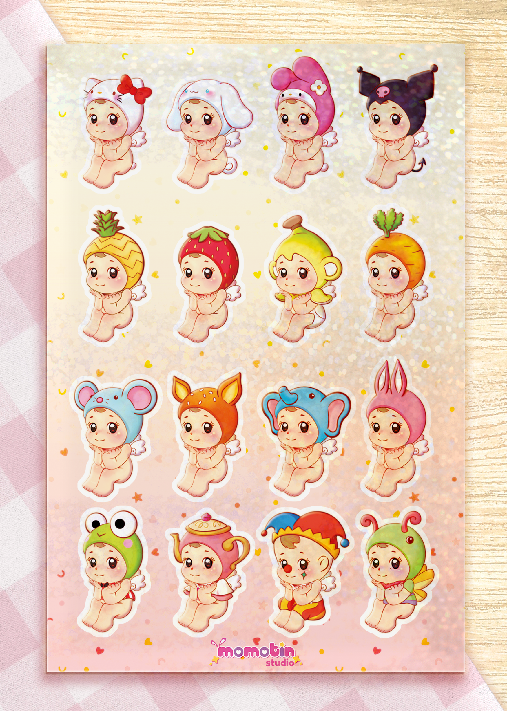 A sheet of cute cartoon baby stickers arranged in a grid on a pink glittery laminate. Each sticker shows a different adorable character in various playful outfits and animal or fruit-inspired costumes.