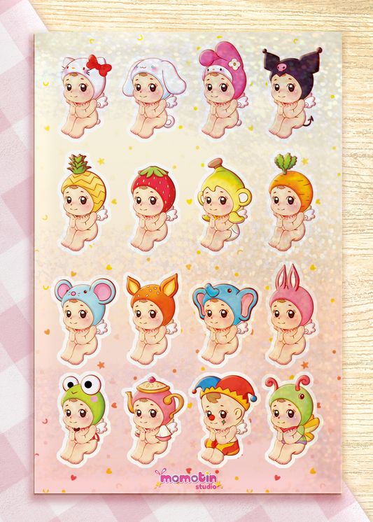 A sheet of cute cartoon baby stickers arranged in a grid on a pink glittery laminate. Each sticker shows a different adorable character in various playful outfits and animal or fruit-inspired costumes.